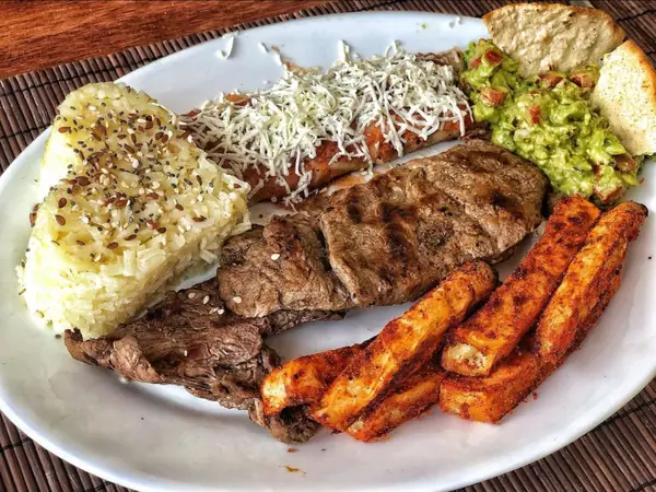 Plato con carne asada, arroz, enchilada y guacamole